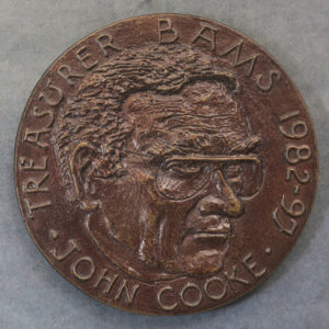 GB Ron Dutton, John Cook, 1982-97 BAMS Treasurer, portrait, rev. symbols evoking John’s life - the car and caravan with which John and Audrey Cook travelled all over Europe, including visiting congresses in Finland and Hungary, the account books, and lots of medals. cast bronze 64mm